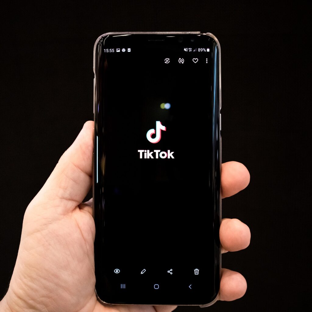 Main tenant un smartphone affichant le logo TikTok.