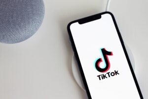 Smartphone affichant le logo TikTok posé sur un chargeur.