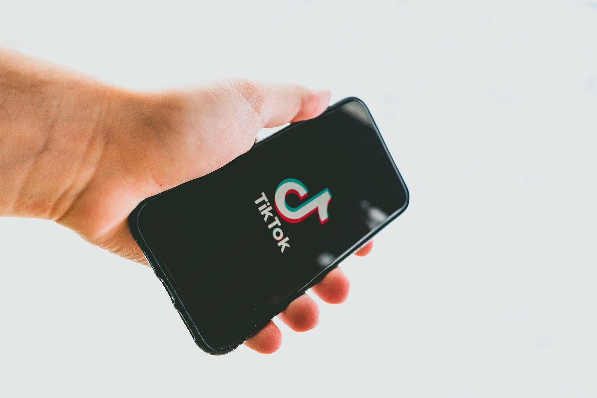 Main tenant un smartphone affichant le logo TikTok.